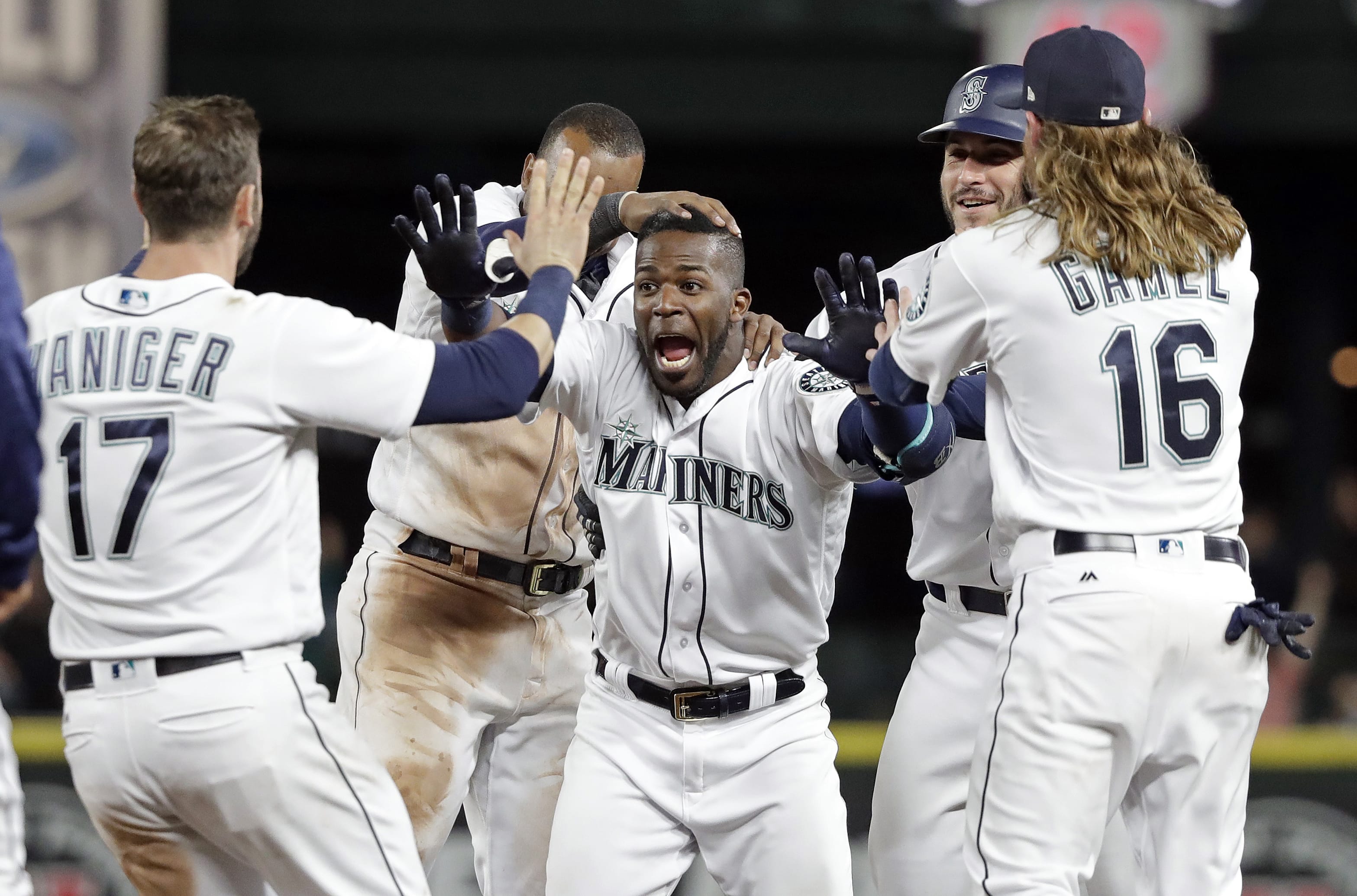 Seattle Mariners' Guillermo Heredia, center, is cheered by teammates after hitting a one-run single to beat the Texas Rangers in the 11th inning of a baseball game Tuesday, May 15, 2018, in Seattle. The Mariners won 9-8.