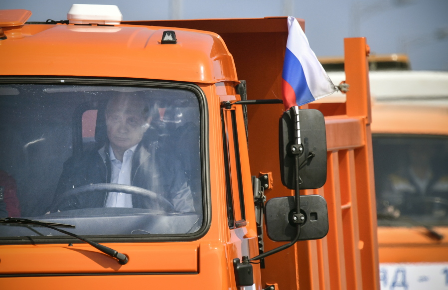 Above, Russian President Vladimir Putin drives a truck to officially open the new bridge linking Russia and the Crimean peninsula Tuesday near Kerch, Crimea. The bridge, left, took two years to build and cost $3.6 billion.