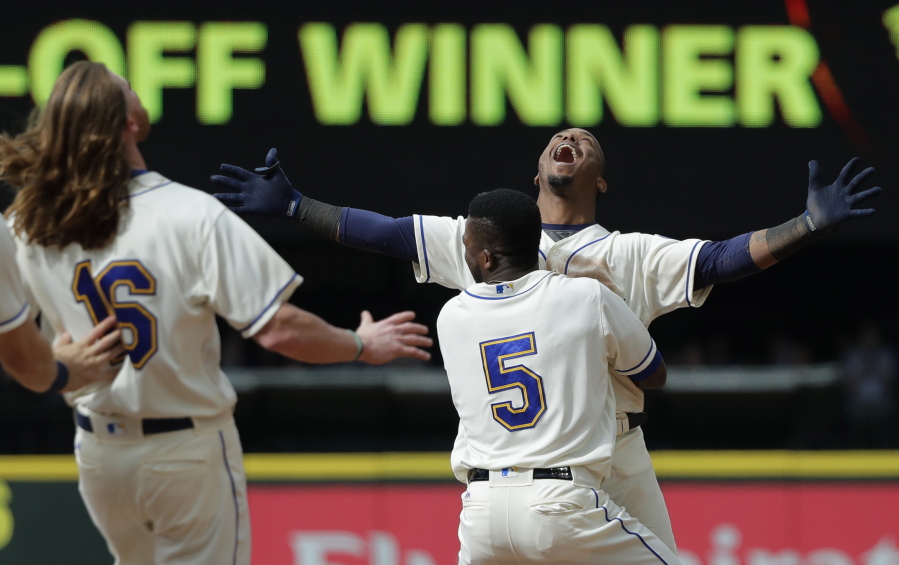 Seattle Mariners’ Jean Segura, right, celebrates with Guillermo Heredia (5) and Ben Gamel, left, after hitting a walkoff RBI-single to score Dee Gordon and give them a victory over the Detroit Tigers in the 11th inning of a baseball game Sunday, May 20, 2018, in Seattle. (AP Photo/Ted S.