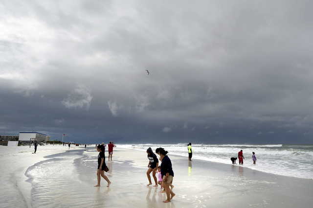 Beachgoers walk on Okaloosa Island in Fort Walton Beach, Fla., Monday, May 28, 2018, as Subtropical Storm Alberto approaches the Gulf Coast. The storm's gusty rain and brisk winds roiled the seas near the U.S. Gulf Coast on Monday, keeping white sandy beaches emptied of their usual Memorial Day crowds.