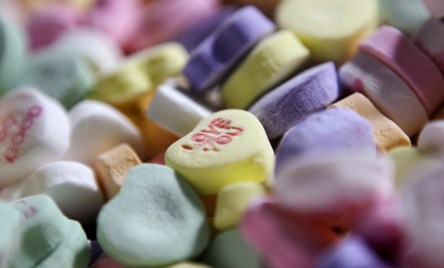 Colored “Sweethearts” candy is held in bulk prior to packaging at the New England Confectionery Company in Revere, Mass.