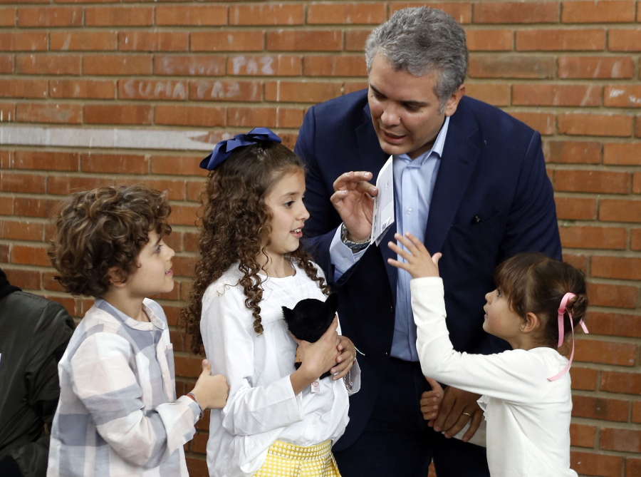 Ivan Duque, presidential candidate with the Democratic Center party, shows his ballot to his children before they help him place it in the ballot box, during the presidential election in Bogota, Colombia, Sunday, May 27, 2018. Leading the polls is the conservative former senator, the protege of former President Alvaro Uribe.