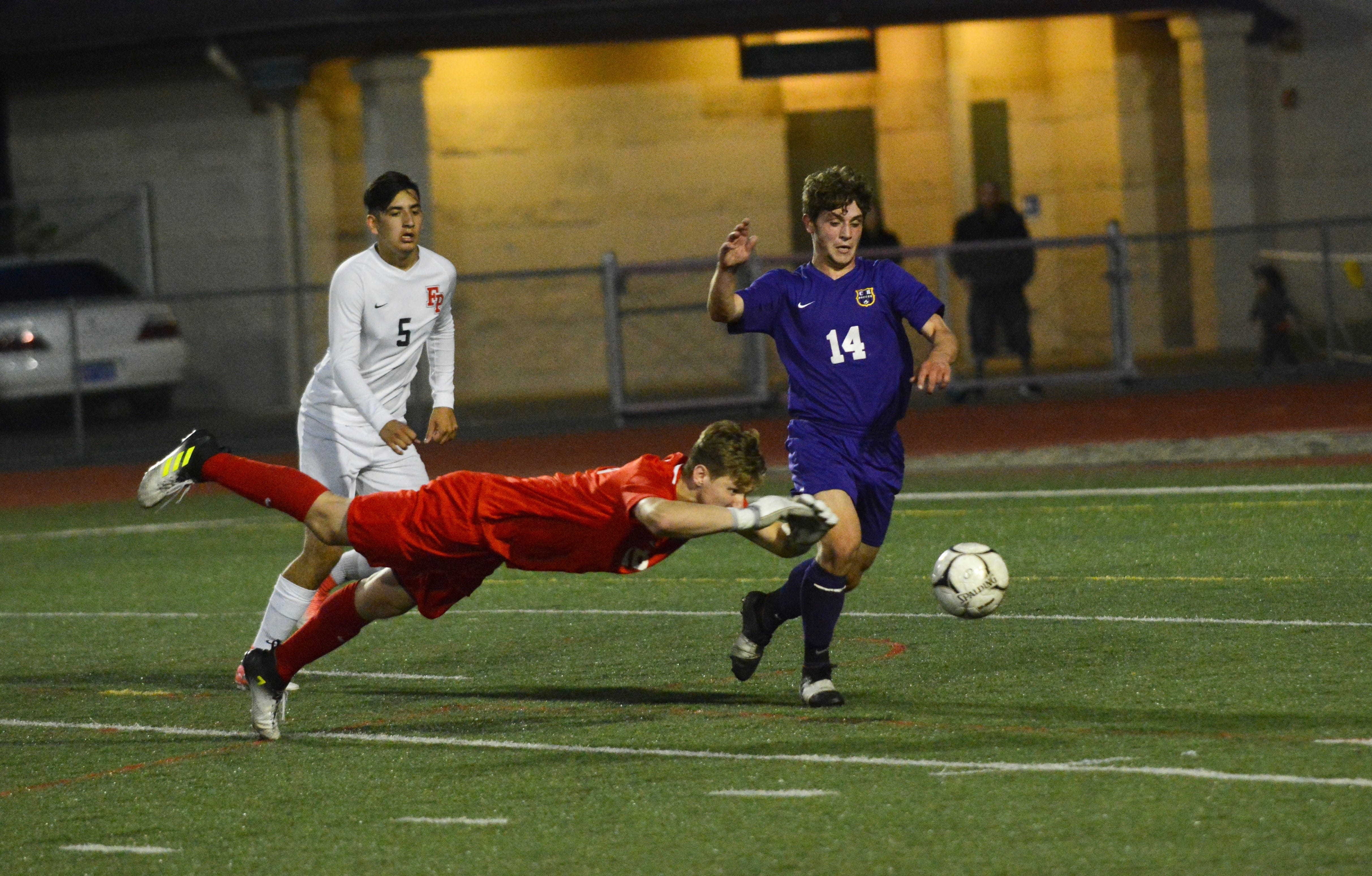 Columbia River forward Jake Connop (right) lunges for a loose ball while Franklin Pierce goalkeeper Noah Carver dives in the first half of the 2A state semifinal at Sumner High School on Friday, May 25, 2018.