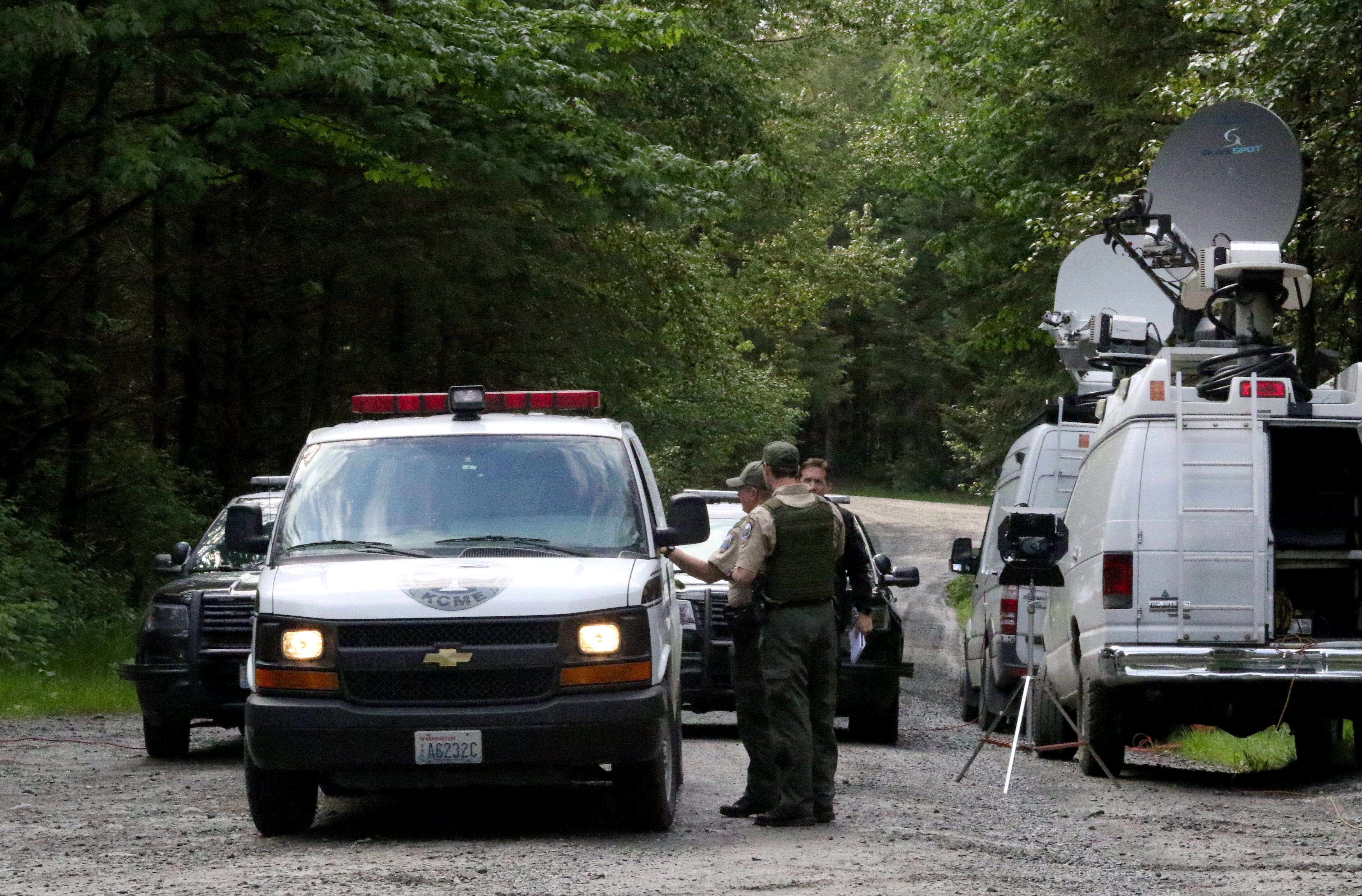 Washington State Fish and Wildlife Police confer with an individual from the King County Medical Examiner's office on a remote gravel road above Snoqualmie, Wash., following a fatal cougar attack, Saturday, May 19, 2018.  One man was killed and another seriously injured when they encountered a cougar Saturday while mountain biking in Washington state, officials said.