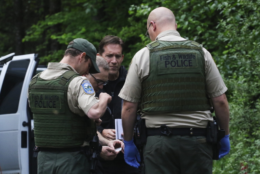 Washington State Fish and Wildlife Police confer with an individual from the King County Medical Examiner’s and a King County Sheriff’s deputy on a remote gravel road above Snoqualmie,following a fatal cougar attack Saturday. One man was killed and another seriously injured when they encountered a cougar Saturday while mountain biking in Washington state, officials said.