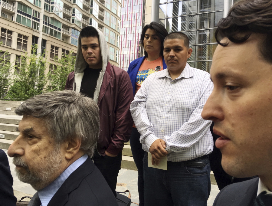 FILE - In this May 1, 2018 file photo Daniel Ramirez Medina, center right, listens as two of his lawyers, Mark Rosenbaum, left, and Nathaniel Bach, right, address reporters following a hearing in U.S. District Court in Seattle. A federal judge in Seattle has at least temporarily blocked the government from revoking Medina’s enrollment in a program designed to protect those brought to the United States illegally as children. Medina’s participation in the Deferred Action for Childhood Arrivals program was due to expire Tuesday, May 15, 2018, U.S. District Judge Ricardo S. Martinez ordered U.S. Citizenship and Immigration Services to maintain Medina’s status.