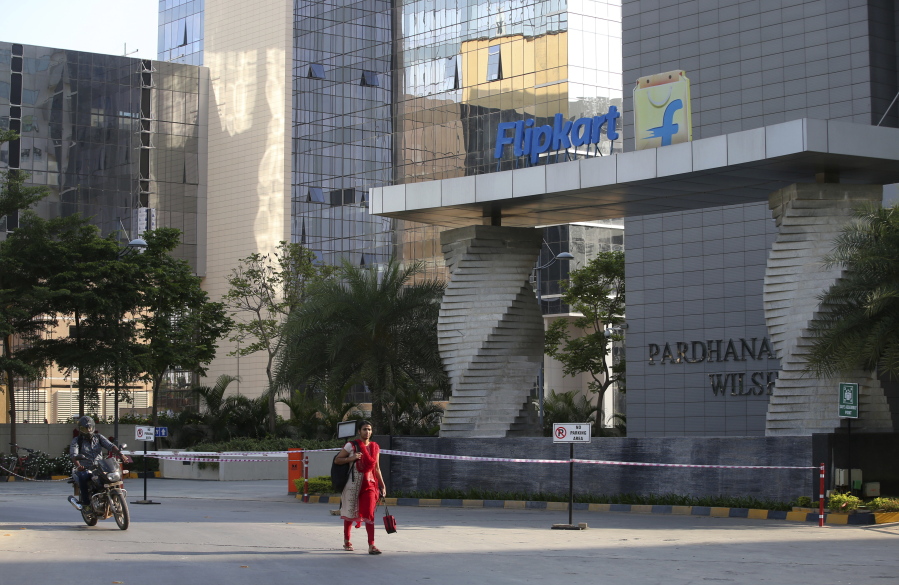 A motorist and a woman pass a building that formerly was the Flipkart headquarters Wednesday in Bangalore, India. Walmart is paying $16 billion for a controlling stake in India’s giant online retailer Flipkart, breaking into a fast-growing economy where it has struggled to establish a foothold.