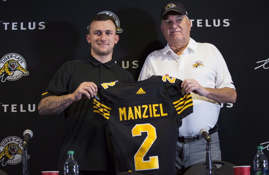 Former NFL quarterback and Heisman Trophy winner Johnny Manziel, left, holds a jersey with Hamilton Tiger-Cats head coach June Jones after announcing that he has signed a two-year contract to play for the CFL team at a press conference in Hamilton, Ontario, Saturday, May 19, 2018.
