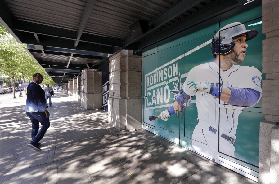 A man walks past an oversized photo of Seattle Mariners second baseman Robinson Cano outside the stadium before the team’s baseball game against the Texas Rangers on Tuesday, May 15, 2018, in Seattle. Cano was suspended 80 games for violating baseball’s joint drug agreement.