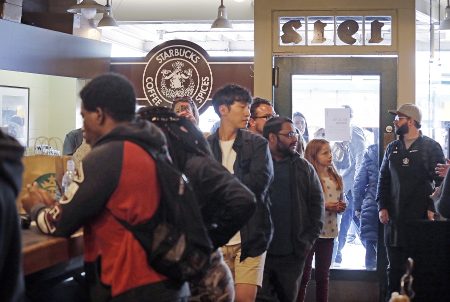 The final customers of the day line-up inside the Pike Place Market Starbucks, commonly referred to as the original Starbucks, after the doors were shut behind them Tuesday, May 29, 2018, in Seattle. The first Starbucks cafe was located nearby in the early 1970’s. Starbucks closed more than 8,000 stores nationwide on Tuesday to conduct anti-bias training, the next of many steps the company is taking to try to restore its tarnished image as a hangout where all are welcome.