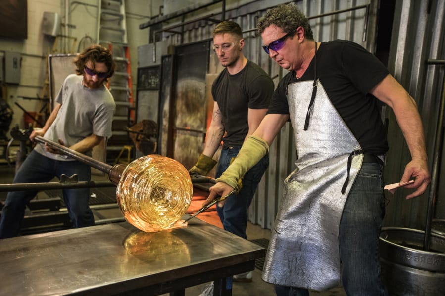 Glass artist Martin Blank guides a freshly poured line of glass onto the sculpture with help from artists Jon Harvey at left and Ronnie Phillips, center, on May 22.