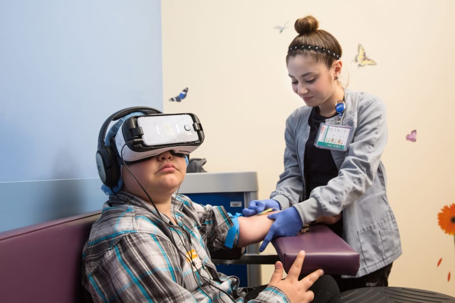 A child uses VR goggles while getting his blood drawn. Such devices allow patients to relax despite the stresses of treatment.