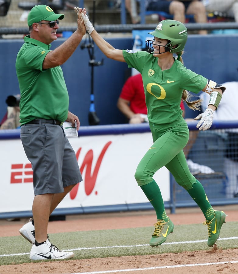Oregon’s Haley Cruse (26) high-fives coach Mike White after hitting a two-run home run against Arizona State in the bottom of the fifth inning during the first game of the NCAA softball Women’s College World Series, in Oklahoma City, Thursday, May 31, 2018.