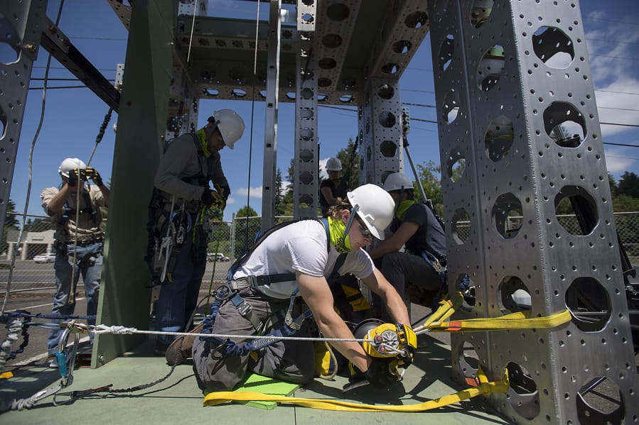 Student Justin Spencer, center in white, performs a simulated rescue while on a wind turbine training tower at the Northwest Renewable Energy Institute. Safety is a focus of student training.