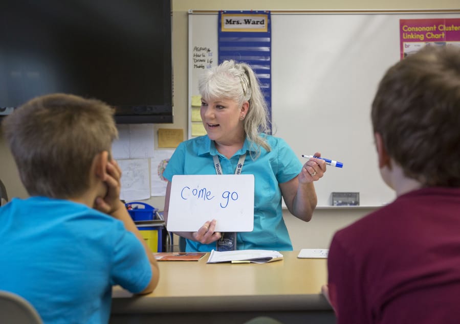 Julie Ward, a paraeducator at Woodburn Elementary School in Camas, helps students learn to read on Thursday. She spends about 25 percent of her days helping students with reading and 75 percent working with students on mathematics.