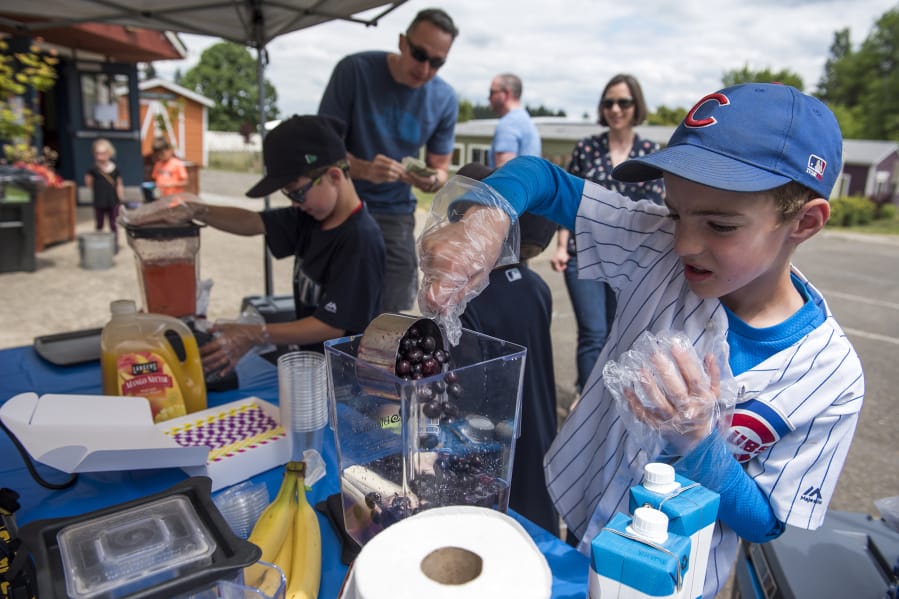 Gardner School second-graders Dashiell Weiss, right, and his Team Smoothie business partner Ben Wheeler, left, make smoothies during the annual Gardner Market on Friday. The event gives the students a chance to become entrepreneurs for a day and help raise money for nonprofits. This year the event will benefit the Eagle Creek Fire Restoration Fund and The Ocean Cleanup.