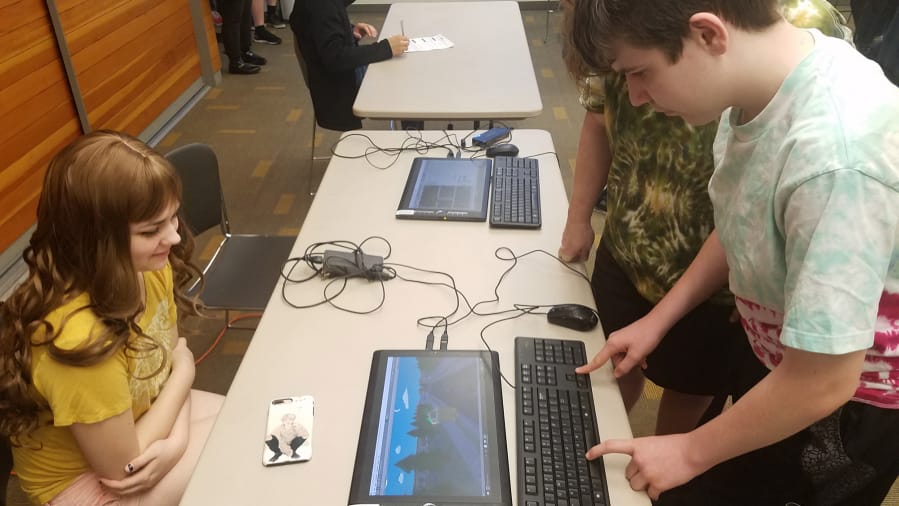 Alina Shcherbakova watches as Joshua Hill plays a video game she created during the school year. Video games and digital apps were on display Saturday at Cascade Park Community Library during Evergreen Public Schools Game Design Expo.