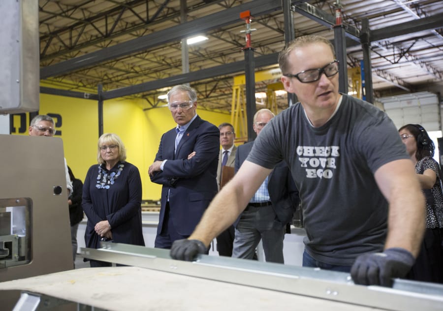Gov. Jay Inslee, center, watch as Bryan Parmenter explains part of the production process at Blokable’s Vancouver plant. The company has its first modular housing units coming online this summer.