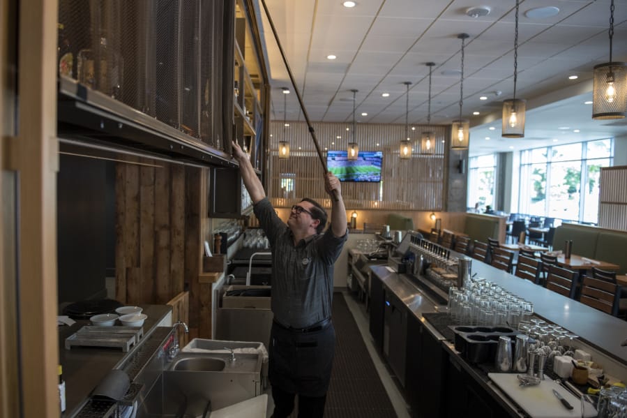 Grays server Aaron Snoddy of Battle Ground opens up the bar area at the restaurant, located at the Hilton Vancouver Washington. The restaurant is finishing up a $1.7 million redesign.