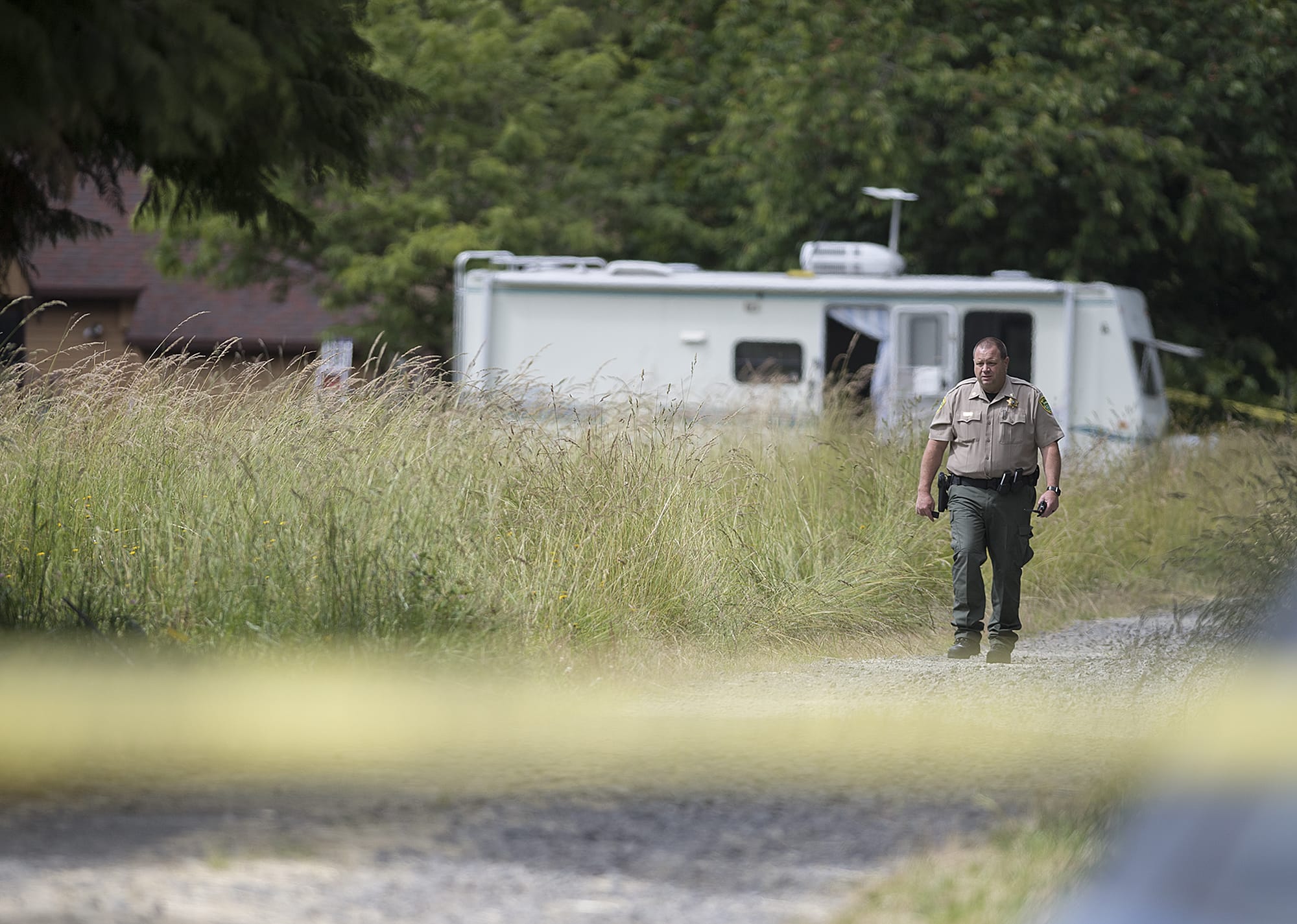 Comm. Duncan Hoss of the Clark County Sheriff's Office walks along the driveway at the scene of an officer-involved shooting in Brush Prairie on Wednesday afternoon, June 13, 2018.