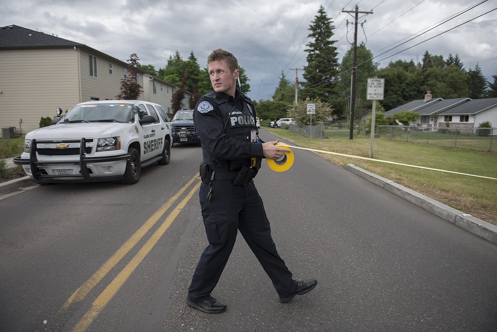 Officer Jason Nicholson puts up crime scene tape at the intersection of Northeast 114th Street and Northeast 124th Avenue after an officer-involved shooting in Brush Prairie on Wednesday afternoon, June 13, 2018. The tape was removed soon after and the intersection was opened.