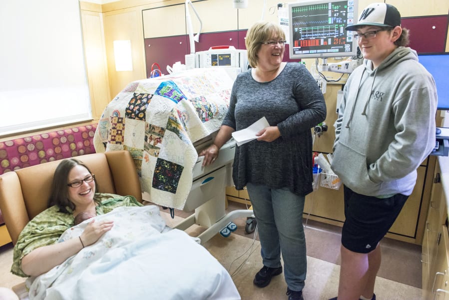 Karrie Keehart, from left, Mary Hylton and Jake Hylton react to a letter written by Jake at the PeaceHealth Southwest Medical Center neonatal intensive care unit in Vancouver. Jake was a premature baby at the hospital 14 years ago, and as part of a class project, he printed 46 letters detailing what the experience was like for his mother when he was born prematurely.