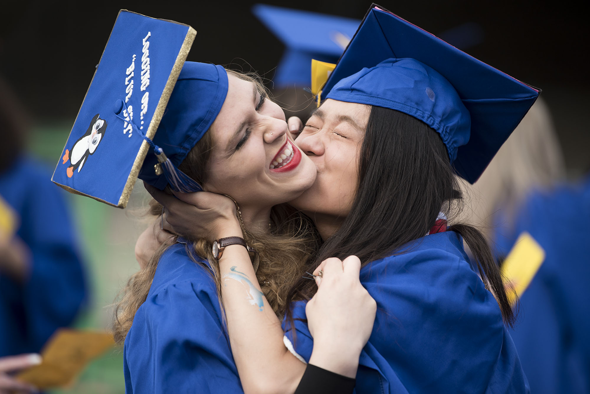 Lydia Straub, left, who is graduating with an Associate of Arts, tries to evade a kiss from Meizhi Teoh, right,  graduating with an Associate of Arts with honors, before the 2018 Clark College Commencement Ceremony at the Sunlight Supply Amphitheater on Thursday evening, June 21, 2018.