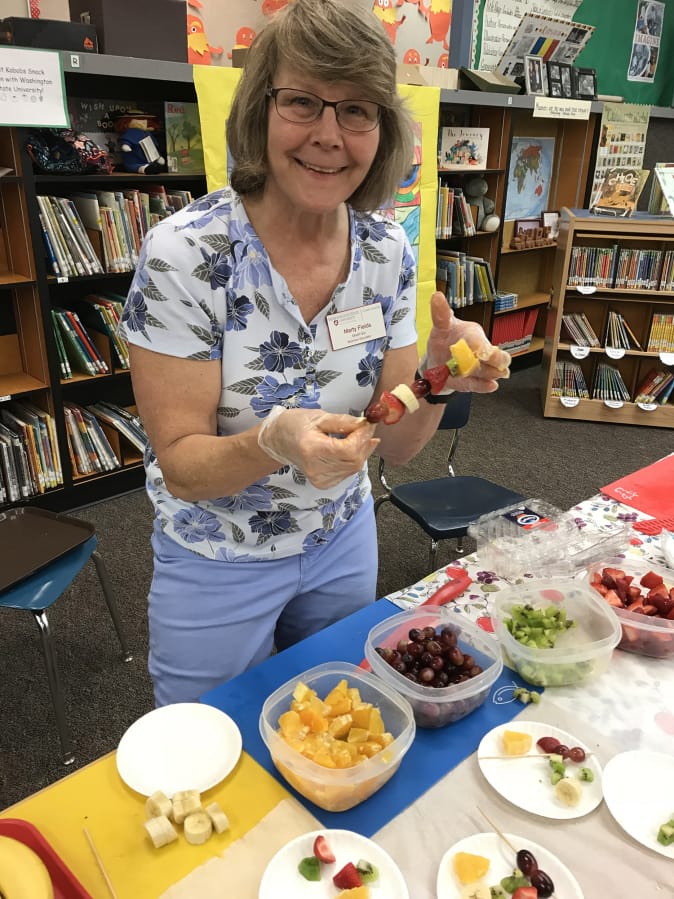 Orchards: Marty Fields, a nutrition educator with Washington State University Extension’s Supplemental Nutrition Assistance Program Education, handed out fruit kabobs to guests at Silver Star Elementary School’s Family Art Show.