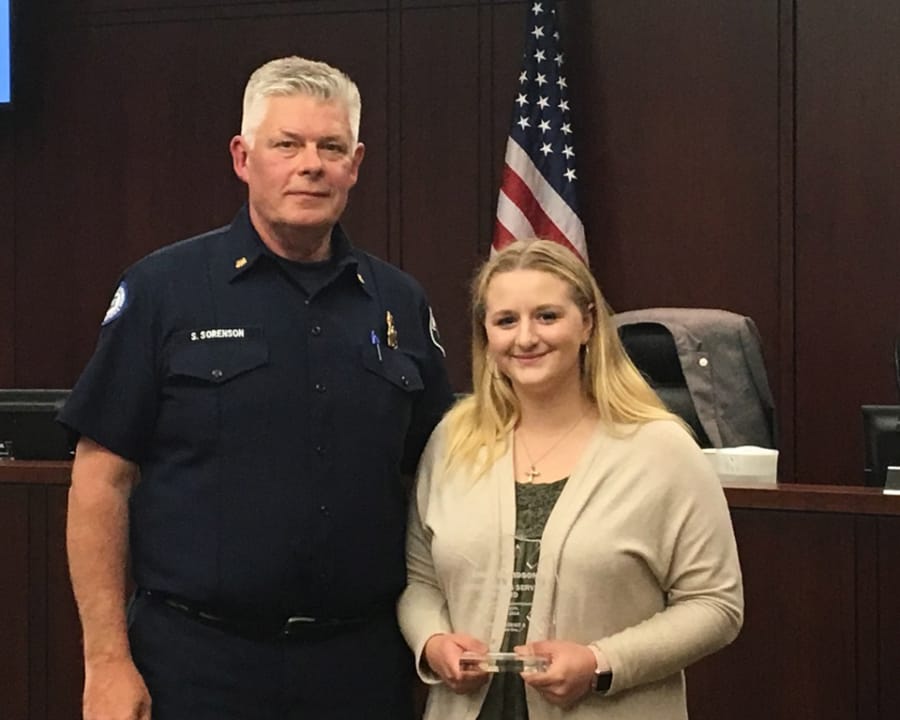Clark County Fire District 3 Chief Scott Sorenson presents Emily Davidson with a plaque honoring her for helping provide first aid to an 82-year-old woman who collapsed at a seniors dance.