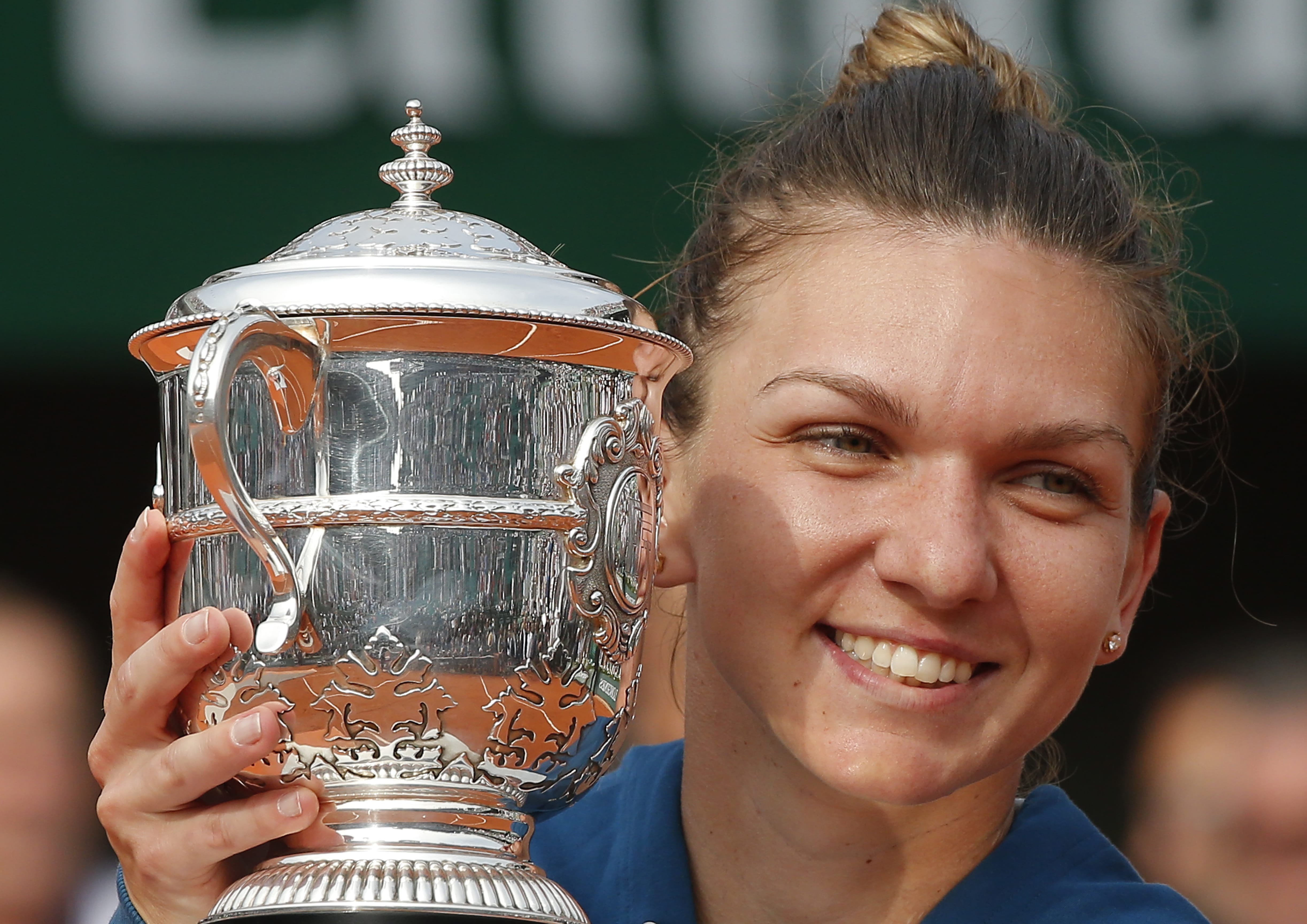 Romania's Simona Halep holds the trophy as she celebrates winning the final match of the French Open tennis tournament against Sloane Stephens of the U.S. in three sets 3-6, 6-4, 6-1, at the Roland Garros stadium in Paris, France, Saturday, June 9, 2018.
