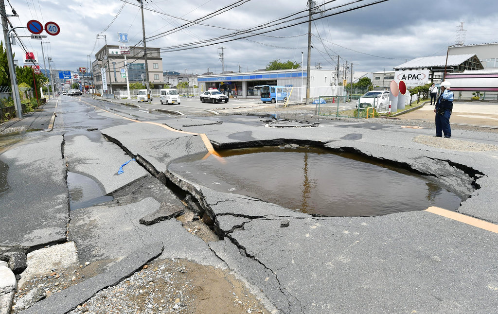 A crack is filled with water on a road after water pipes were broken following an earthquake in Takatsuki city, Osaka, western Japan, Monday, June 18, 2018. A strong earthquake knocked over walls and set off scattered fires around metropolitan Osaka on Monday morning.