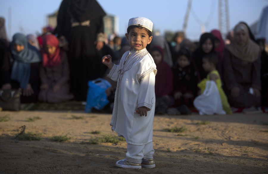 A Palestinian boy wearing a traditional uniform stands in front of Muslim women performing Eid al-Fitr prayers, marking the end of the holy fasting month of Ramadan, in Eastern Gaza City on Friday.