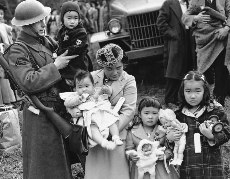 Cpl. George Bushy, left, a member of the military guard which supervised the departure of 237 Japanese people for California, holds the youngest child of Shigeho Kitamoto, center, as she and her children are evacuated from Bainbridge Island, Wash. Throughout American history, during times of war and unrest, authorities have cited various reasons and laws to take children away from their parents. Examples include Native American boarding schools, Japanese internment camps and deportations that happened during the Great Depression.