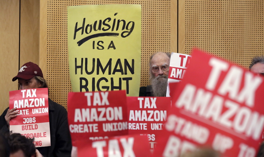 FILE - In this May 14, 2018 file photo, members of the public look on at a Seattle City Council before the council voted to approve a tax on large businesses such as Amazon and Starbucks to fight homelessness in Seattle. Amazon, Starbucks, Vulcan and a few dozen others have pledged more than $350,000 toward an effort to repeal Seattle’s newly passed tax on large employers to combat homelessness.