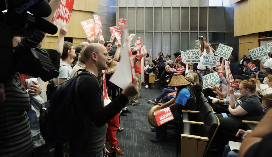 Supporters, at left, of a tax on large companies that was intended to combat a growing homelessness crisis stand in Seattle City Council chambers Tuesday and face off against people at right supporting the repeal of the tax. TED S.