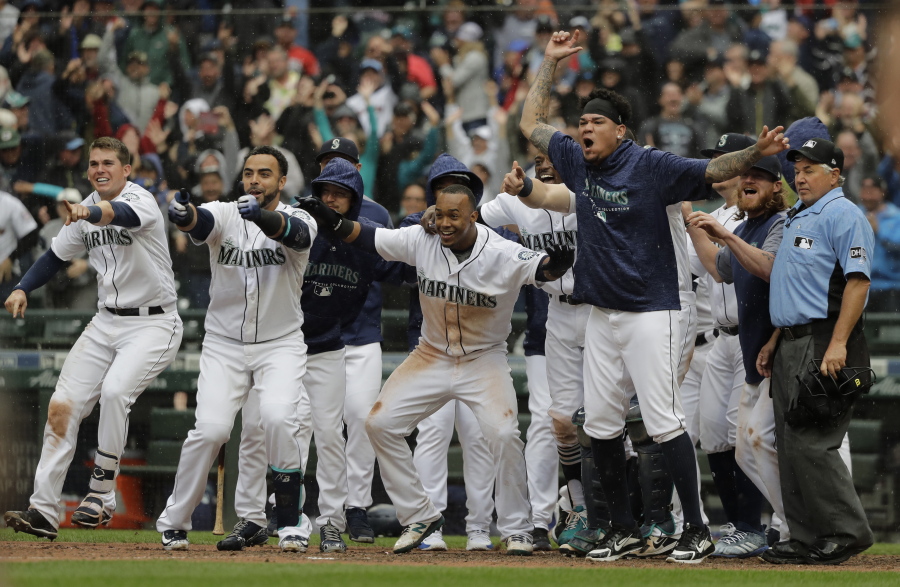 Seattle Mariners. including Jean Segura, center, who scored the game-winning run on a two-run walk-off home run by Mitch Haniger, wait for Haniger at the plate during the ninth inning of a baseball game against the Los Angeles Angels, Wednesday, June 13, 2018, in Seattle. The Mariners won 8-6. (AP Photo/Ted S.