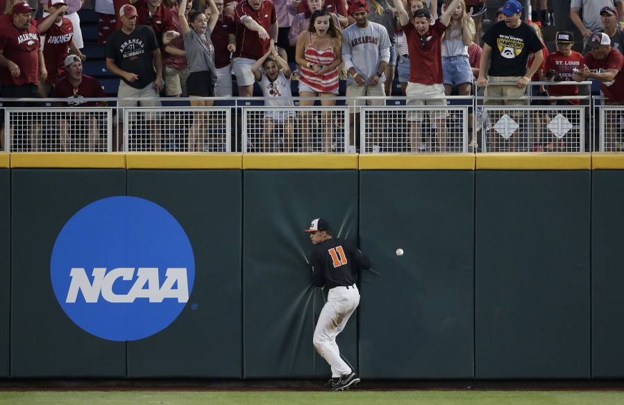 Oregon State right fielder Trevor Larnach (11) hits the wall on a double by Arkansas’ Dominic Fletcher during the seventh inning of Game 1 of the NCAA College World Series baseball finals in Omaha, Neb., Tuesday. Arkansas won 4-1 to take the lead in the best-of-three series.