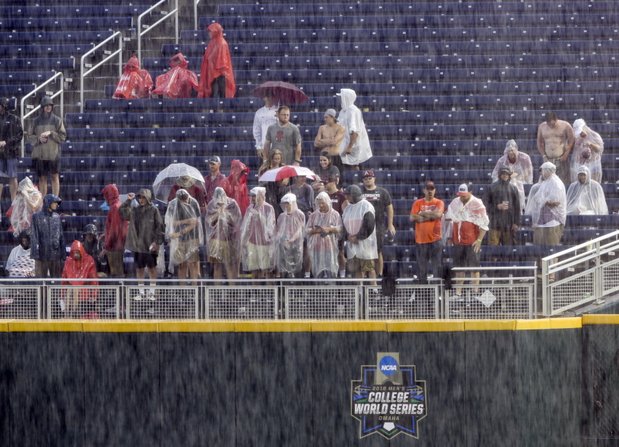Spectators wait in the rain during a rain delay before Game 1 of the NCAA College World Series baseball finals between Oregon State and Arkansas, in Omaha, Neb in Omaha, Neb., Monday, June 25, 2018. Game 1 has been rescheduled for Tuesday.