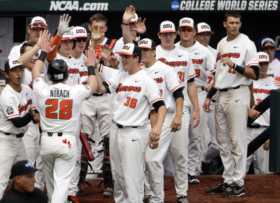 Oregon State’s Kyle Nobach (28) is greeted at the dugout after he scored against Mississippi State on a one-run single by Michael Gretler in the second inning of an NCAA College World Series baseball game in Omaha, Neb., Friday, June 22, 2018.