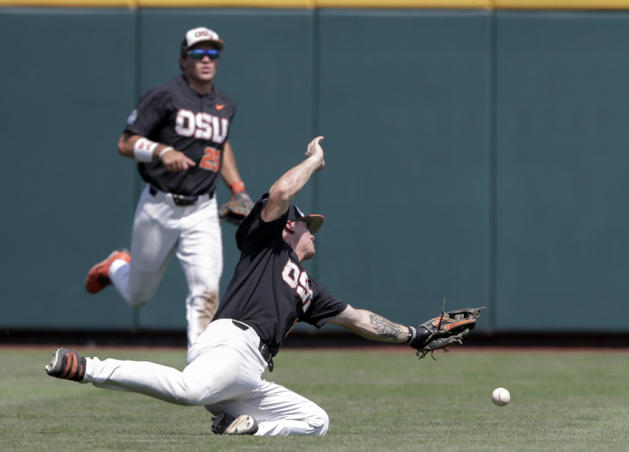 Oregon State shortstop Cadyn Grenier, foreground, leaps for but misses the ball hit for a single by North Carolina’s Ike Freeman in the third inning of an NCAA College World Series baseball game in Omaha, Neb., Saturday, June 16, 2018. Oregon State left fielder Jack Anderson (29) looks on.