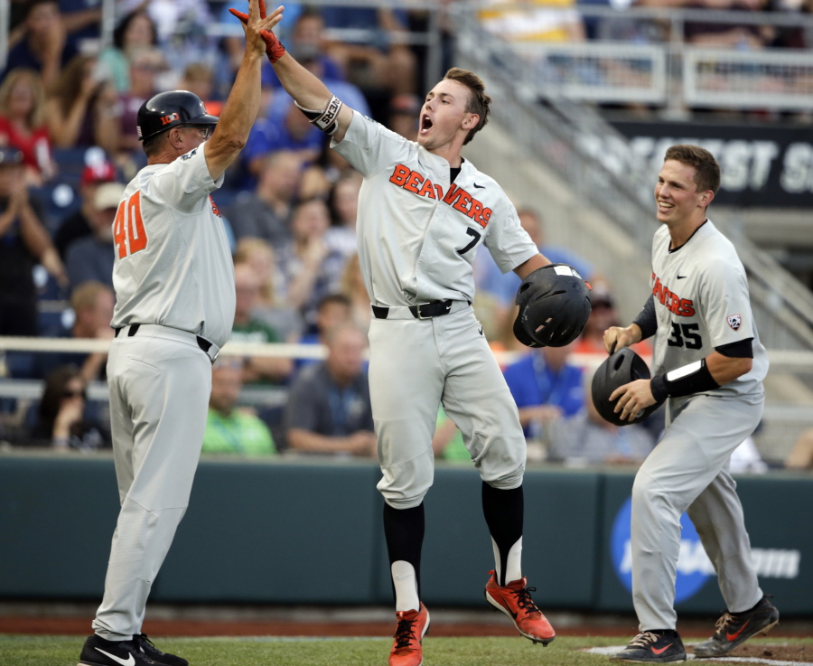 Oregon State’s Tyler Malone (7) celebrates with Adley Rutschman (35) and Michael Attalah (40) after hitting a three-run home run against Mississippi State in the third inning. The blast capped a five-run inning that led the Beavers back to the College World Series finals to face Arkansas.