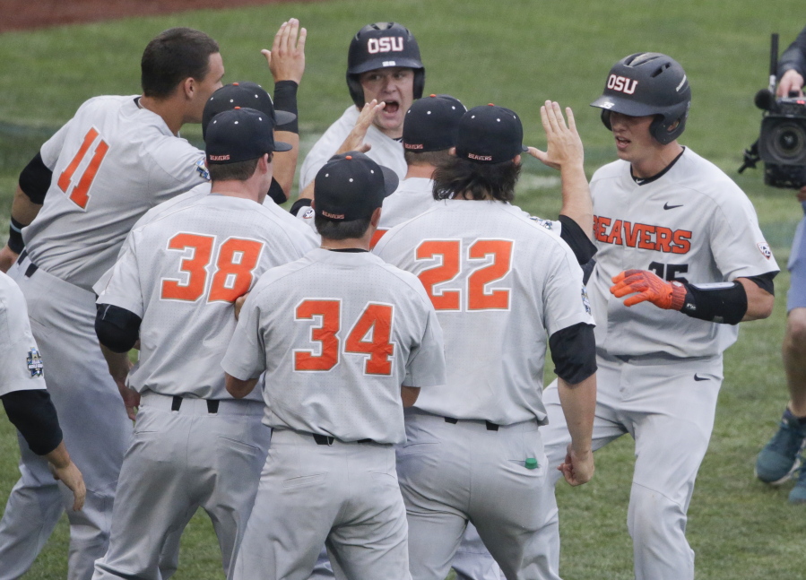 Oregon State’s Adley Rutschman, right, is congratulated near the dugout after his solo home run against North Carolina during the first inning of an NCAA College World Series baseball elimination game in Omaha, Neb., Wednesday, June 20, 2018.