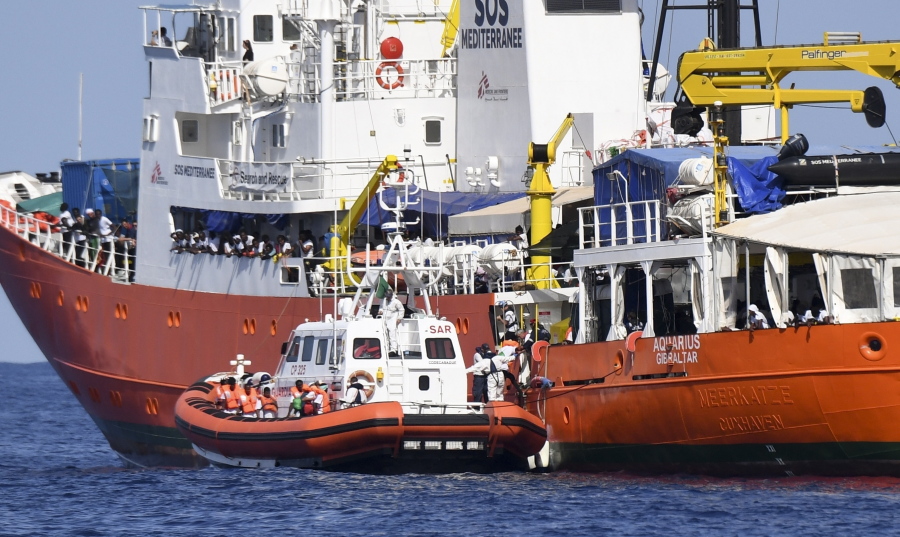 FILE - In this Tuesday, June 12, 2018 file photo, an Italian Coast Guard boat approaches the French NGO “SOS Mediterranee” Aquarius ship as migrants are being transferred, in the Mediterranean Sea. Italy dispatched two ships Tuesday to help take 629 migrants stuck off its shores on the days-long voyage to Spain after the new populist government refused them safe port in a dramatic bid to force Europe to share the burden of unrelenting arrivals.