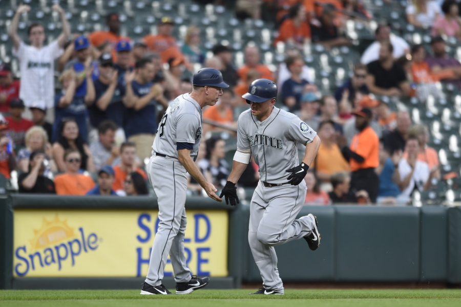 Seattle Mariners' Kyle Seager, right, is congratulated by third base coach Scott Brosius after hitting a solo home run during the fourth inning of baseball game Tuesday, June 26, 2018, in Baltimore.