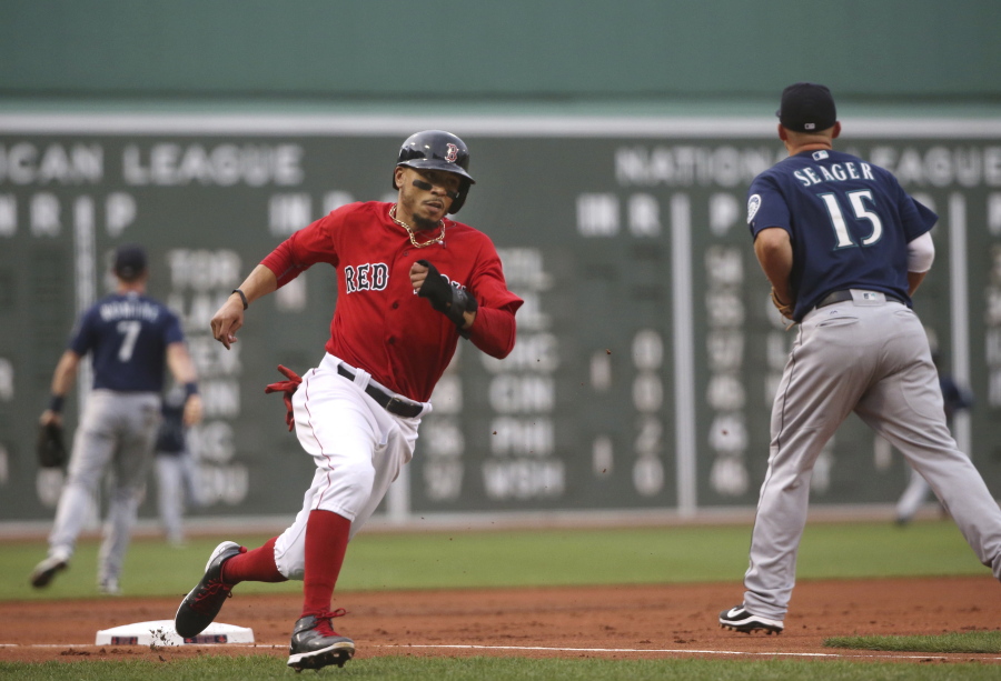 Boston Red Sox's Mookie Betts rounds third past Seattle Mariners third baseman Kyle Seager (15) to score on a double by J.D. Martinez in the first inning of a baseball game at Fenway Park, Friday, June 22, 2018, in Boston.