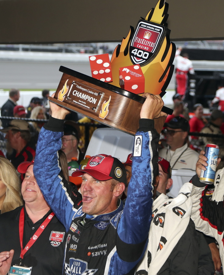 Clint Bowyer holds the Firekeepers Casino 400 trophy after winning a shortened NASCAR Cup Series auto race, Sunday, June 10, 2018, in Brooklyn, Mich.