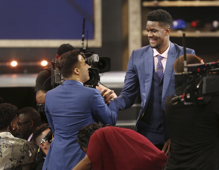 Arizona’s Deandre Ayton, right, is congratulated by friends and family after he was picked first overall by the Phoenix Suns during the NBA basketball draft in New York, Thursday, June 21, 2018.
