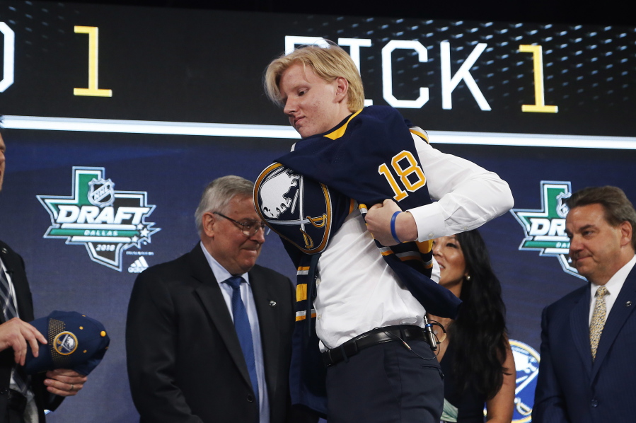 Rasmus Dahlin, of Sweden, puts on a jersey after being selected by the Buffalo Sabres during the NHL hockey draft in Dallas, Friday, June 22, 2018.