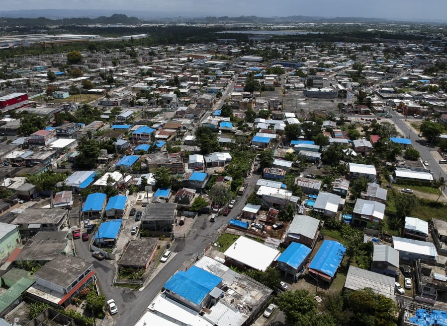 An aerial photo of the Amelia neighborhood east of San Juan, Puerto Rico, taken Monday shows a number of buildings protected with blue plastic tarps, nine months after Hurricane Maria devastated the island. dennis m.