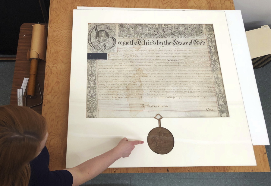 In this May 24, 2018 photo, Rhode Island State Archivist Ashley Selima points to the seal of King George III on a September 1772 proclamation in Providence, R.I. The document established a commission to investigate the burning of the British schooner HMS Gaspee by colonists in Narraganset Bay in June 1772.